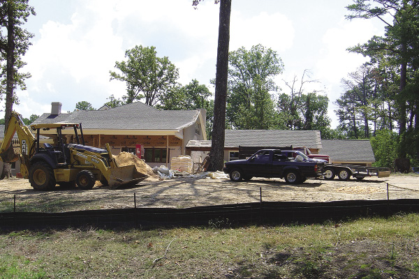 Trucks and heavy equipment parked around a house under construction.